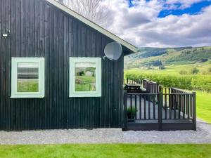 una casa negra con ventanas blancas y un balcón en Tay Lodge, en Aberfeldy 4 fotos más