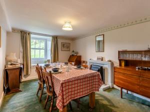 een eetkamer met een tafel en een open haard bij Haweswater Cottage in Bampton