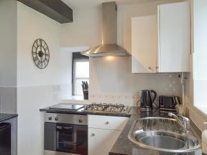 a kitchen with a sink and a stove at Weavers Houses - Uk12796 in Hayfield +4 photos