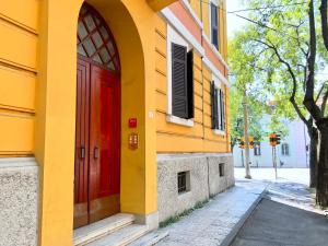 モデナにあるRed Collection, Boutiques Rooms & Suites, Modena City Centerの通りにある赤いドアの付いたオレンジ色の建物
