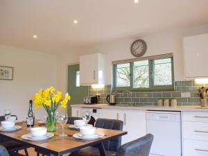 a kitchen with a table and a clock on the wall at Red Kite Lodge - Uk32610 in Old Radnor +16 photos
