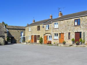 une rangée de maisons en briques avec des portes orange et une allée dans l'établissement Crown Courtyard Cottage, à Grewelthorpe 5 autres photos
