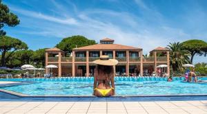 una donna con un cappello seduta in piscina in un resort di Sweet Home Isolotto - direttamente sulla spiaggia ad Albinia Altre 8 foto