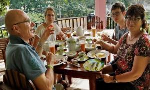 a group of people sitting around a table eating food at Little heaven guest in Ella