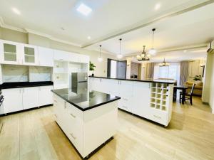 an open kitchen with white cabinets and a dining room at May Homes III in Kampala +12 photos