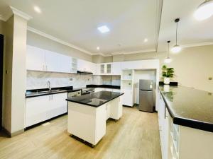 a large kitchen with white cabinets and black counter tops at May Homes III in Kampala