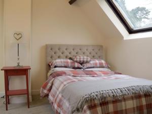 una camera da letto con un letto con una coperta scozzese e una finestra di The Boyne Arms Cottage a Burwarton