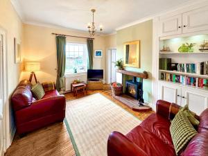 a living room with two red couches and a fireplace at Lighthouse Cottage in Happisburgh