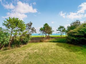 a field with trees and the ocean in the background at Lighthouse Cottage in Happisburgh