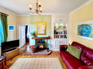 a living room with a red couch and a fireplace at Lighthouse Cottage in Happisburgh +11 photos