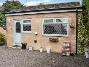 a brick house with a blue door and some potted plants at Puffin Cottage in Amble