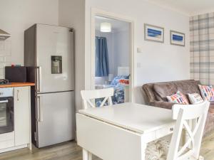 a kitchen with a refrigerator and a table and chairs at Puffin Cottage in Amble