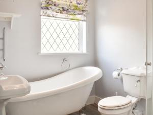 a bathroom with a tub and a toilet and a window at Puffin Cottage in Amble +4 photos