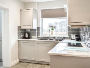 a white kitchen with a sink and a window at Corner Farm - Uk41369 in Carnaby