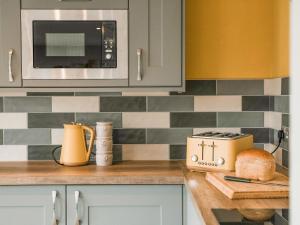 a kitchen with a counter top with a toaster and a microwave at Swallow Lodge - Uk42540 in Winforton