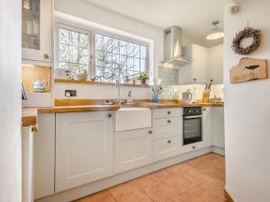 a kitchen with white cabinets and a window at Little Crawfish Cottage in Thursford