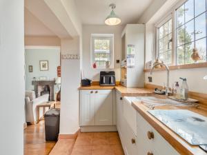 a kitchen with white cabinets and a sink at Little Crawfish Cottage in Thursford