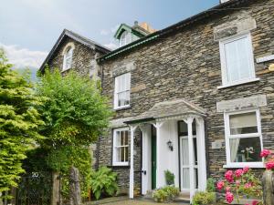 ein altes Steinhaus mit einer weißen Tür in der Unterkunft 18 In The Corner in Windermere