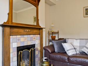 ein Wohnzimmer mit einem Sofa und einem Spiegel über einem Kamin in der Unterkunft 18 In The Corner in Windermere