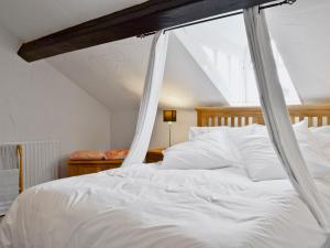 ein Schlafzimmer mit einem weißen Bett mit einem hölzernen Baldachin in der Unterkunft 18 In The Corner in Windermere + 7 Fotos