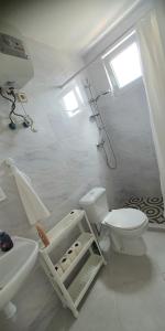 a white bathroom with a toilet and a sink at Residência Alto Saco, Double room with private bathroom in Tarrafal