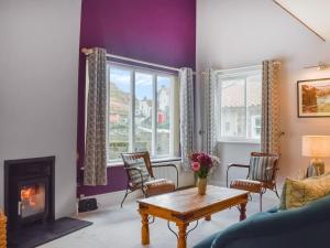 a living room with a fireplace and a table at Pilot Me Cottage in Staithes