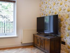 a flat screen tv on a wooden stand in a room with a window at Pilot Me Cottage in Staithes +18 photos