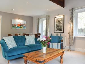 a living room with a blue couch and a wooden table at Pilot Me Cottage in Staithes