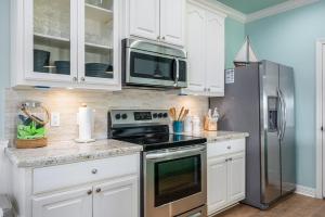 StingareeにあるSea Glass Retreat homeの白いキャビネットとステンレス製の冷蔵庫を備えたキッチン +27枚の写真