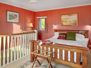 ein Schlafzimmer mit einem Bett in einer roten Wand in der Unterkunft The Cottage At Mains House in Tain