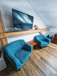 a living room with two blue chairs and a flat screen tv at In Spirit, hotel v Rožnovském pivovaru - Pivní Lázně, Wellness & Čokoládovna in Rožnov pod Radhoštěm