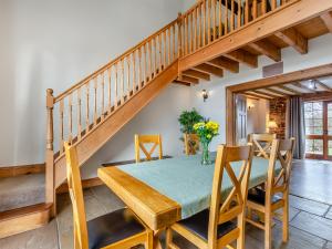 a dining room with a wooden table and a staircase at Barley Store - Uk48910 in Allonby