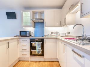 une cuisine avec des armoires blanches et un évier dans l'établissement Bettys Cottage, à New Quay 15 autres photos