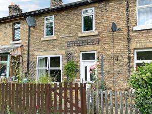 a brick house with a wooden fence in front of it at Railway Cottage in Stanhope