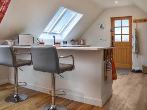 a kitchen with a counter with two chairs and a window at Orchard Loft in Oakham +13 photos