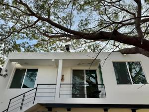 a white house with a tree hanging over it at Comfortable Apt near the Beach in Santa Cruz Huatulco