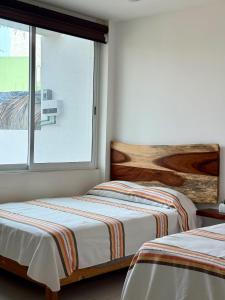 two beds in a room with a window at Comfortable Apt near the Beach in Santa Cruz Huatulco