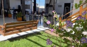 a wooden bench in a yard with purple flowers at Pousada e Restaurante Ponta do Mel in Areia Branca