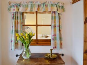 un vase de fleurs sur une table avec une fenêtre dans l'établissement Cefn Canol, à Betws-y-coed 3 autres photos
