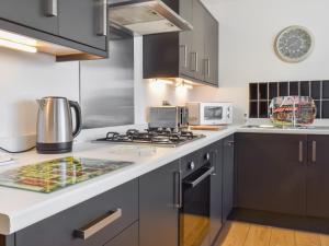 a kitchen with gray cabinets and a stove top oven at Waterside Retreat in Carnforth