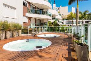 a hot tub on a deck next to a building at Boulevard Bombinhas - Lindíssimo Apartamento em Condo com Piscina e Jacuzzi in Bombinhas
