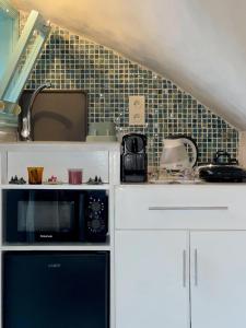 cocina con armarios blancos y microondas negro en Studio Turquesa Kasbah Tangier, en Tánger