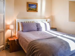 a bedroom with a large bed with blue and white pillows at Tarn Cottage in Grasmere
