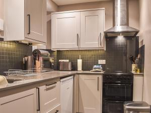 a kitchen with white cabinets and a stove top oven at Tarn Cottage in Grasmere