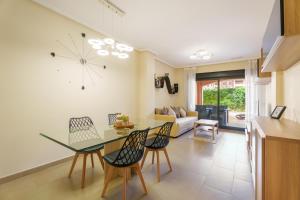 a kitchen and living room with a glass table and chairs at Hogar Brisa de las Marinas acogedor apartamento con amplia terraza y acceso directo a las piscinas-Comfortable apartment with spacious terrace and direct pool access in Denia