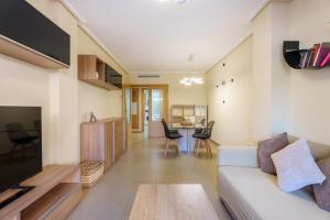 a living room with a couch and a table at Hogar Brisa de las Marinas acogedor apartamento con amplia terraza y acceso directo a las piscinas-Comfortable apartment with spacious terrace and direct pool access in Denia