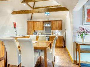 Una cocina con una mesa de madera y sillas blancas. en The Lodge - Uk44516, en North Thoresby