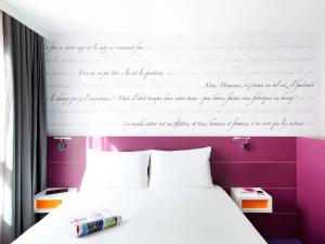 Dormitorio con cama con escrito en la pared en ibis Styles Montpellier Centre Comedie, en Montpellier