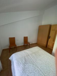 a bedroom with a white bed and two chairs at Casa azul in Nerpio