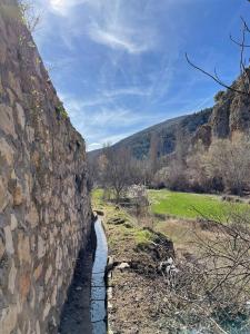 a stone wall next to a river next to a field at Casa azul in Nerpio